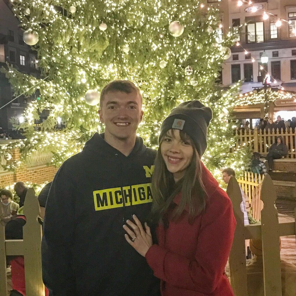 A man and woman standing in front of a Christmas tree. 