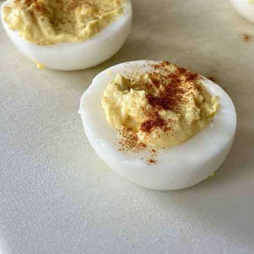 deviled eggs on a white cutting board.