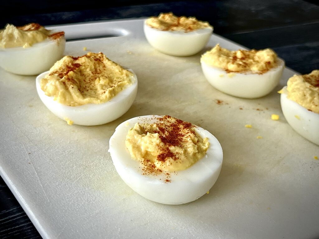 deviled eggs served on a cutting board topped with paprika
