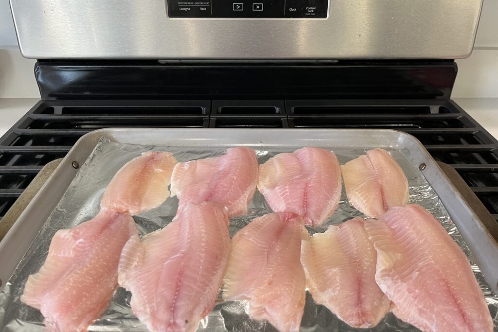 Tilapia fillets on a baking sheet.