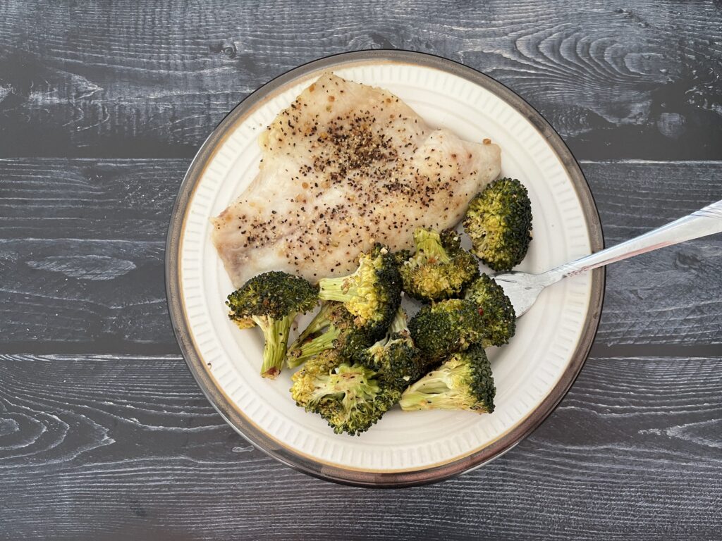 Lemon pepper tilapia served on a plate with roasted broccoli.