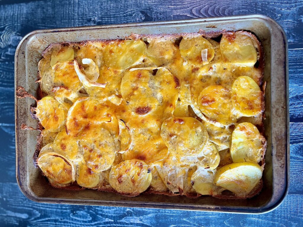Scalloped potatoes with onions, cheese, and sauce.