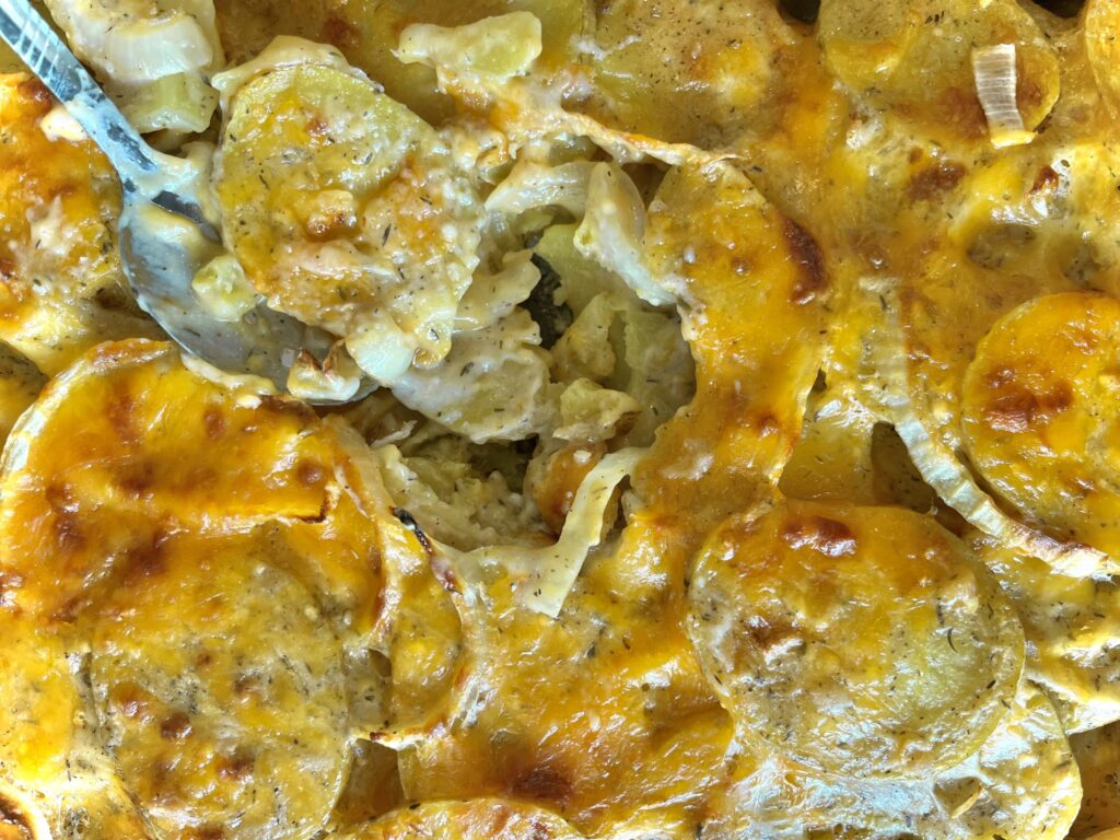Scalloped potatoes scooped out of a baking dish.