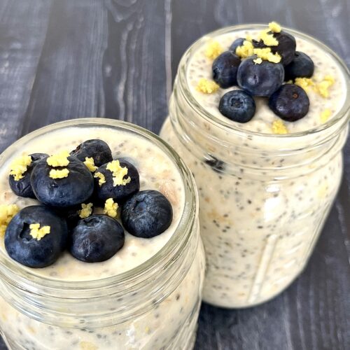 2 glass jars of overnight oats with blueberries and lemon zest on top.