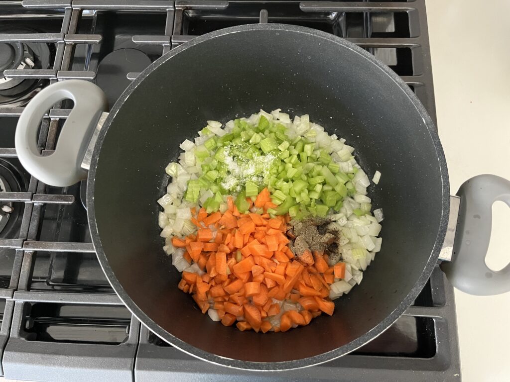 Diced onions, celery, and carrots cooking in a pot.