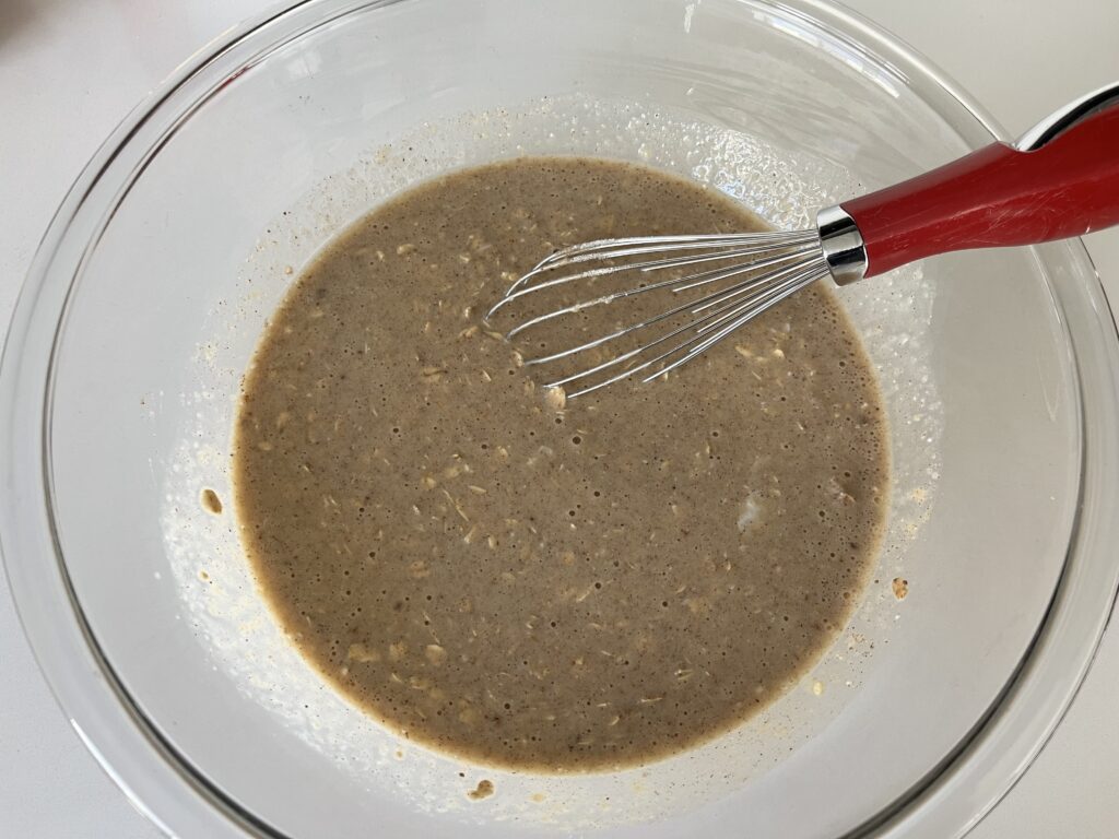 Carrot cake baked oatmeal ingredients mixed in a glass bowl.