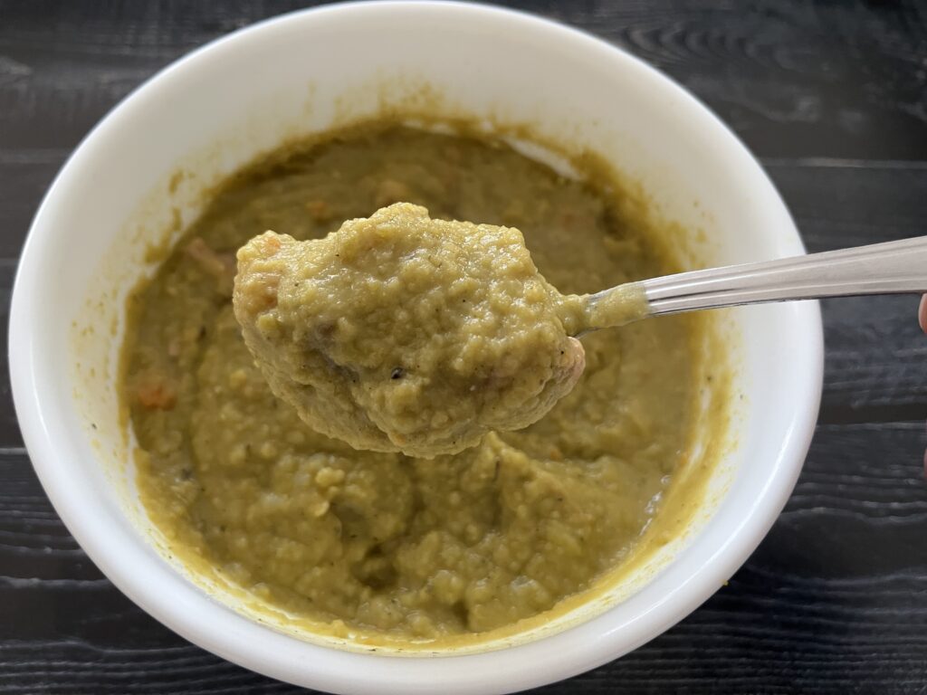 A bowl of split pea soup with ham.