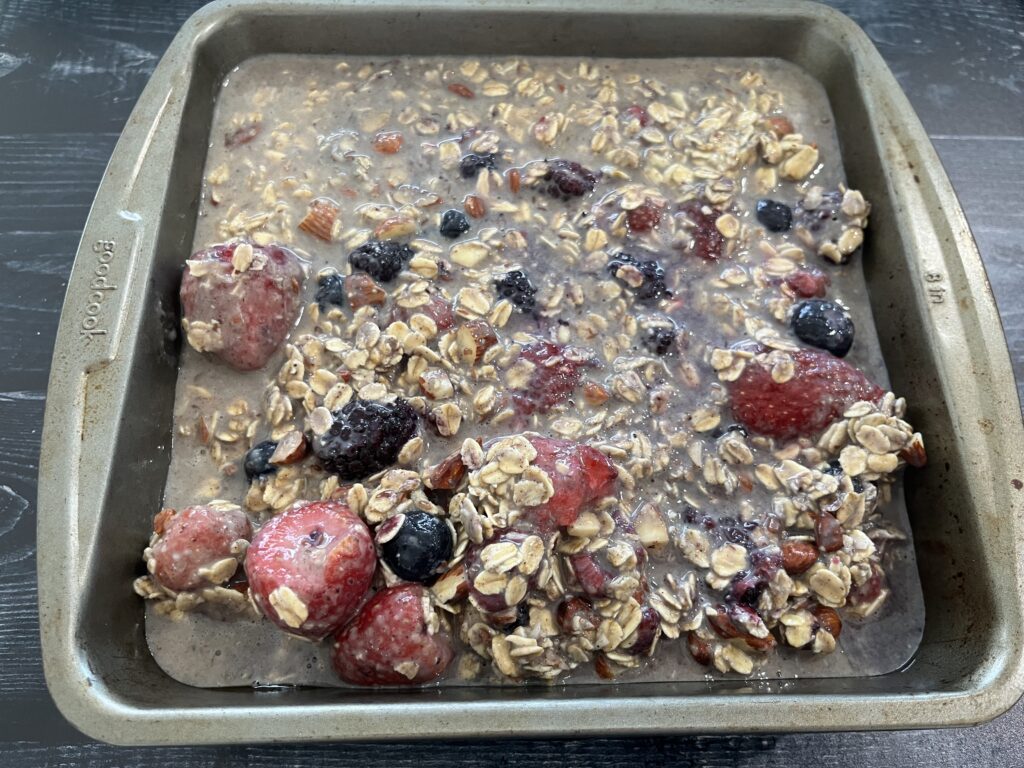 A baking dish with an oatmeal batter with frozen berries.