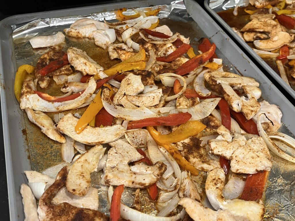 Cooked chicken fajitas on a baking sheet.