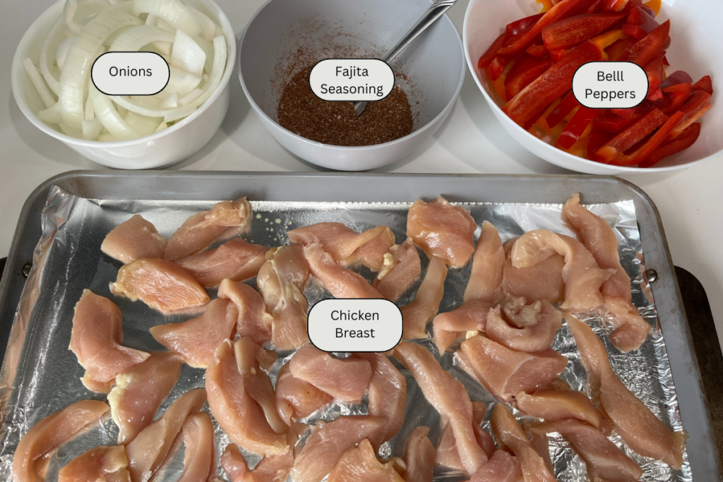 A baking sheet of sliced raw chicken, bowl of sliced peppers and onions and a bowl of spices.