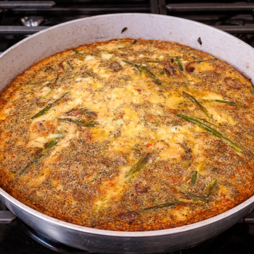 An asparagus mushroom frittata in a skillet on the stove.